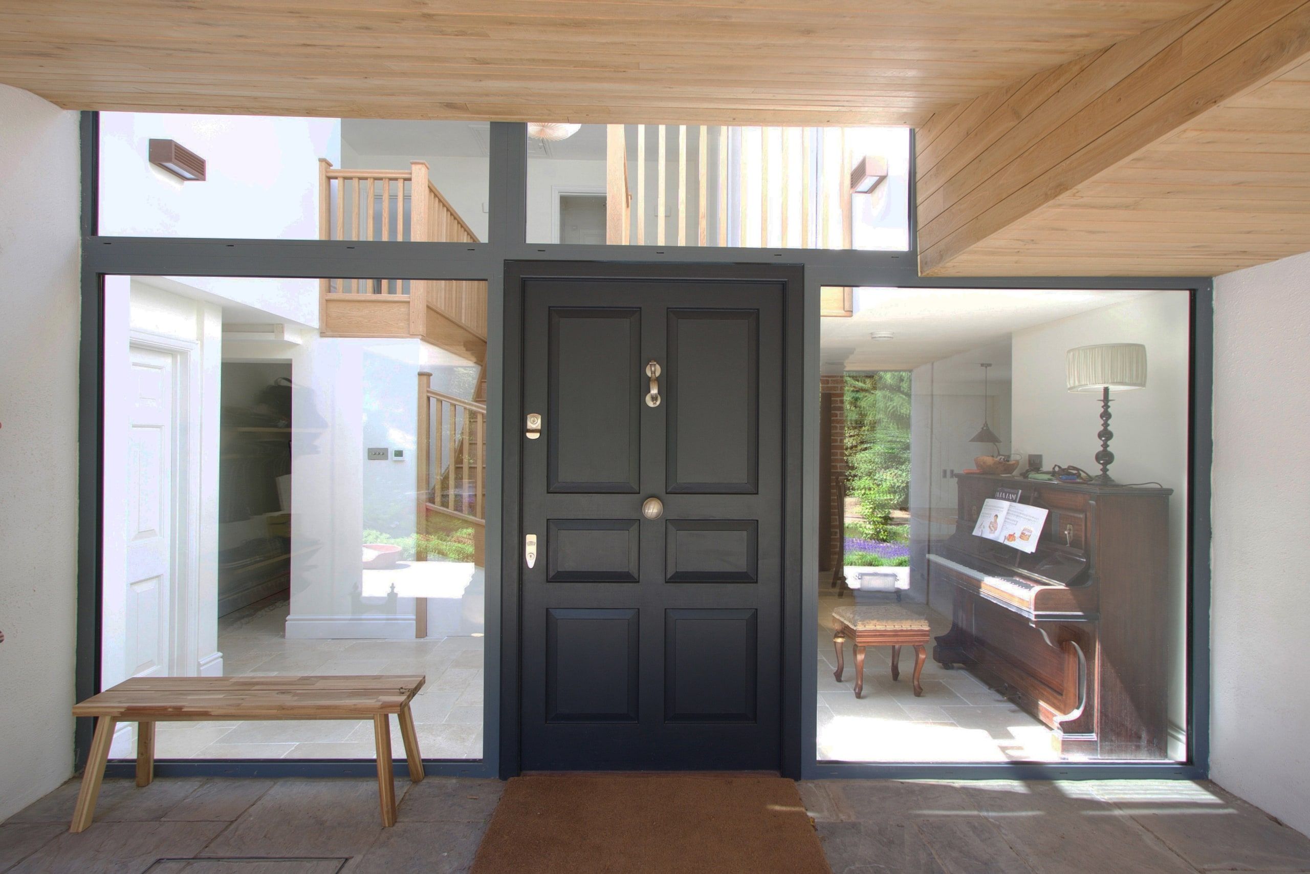 Dark panelled front door set in the full-height glazed entrance hall, 1930s country house, Mole Valley.