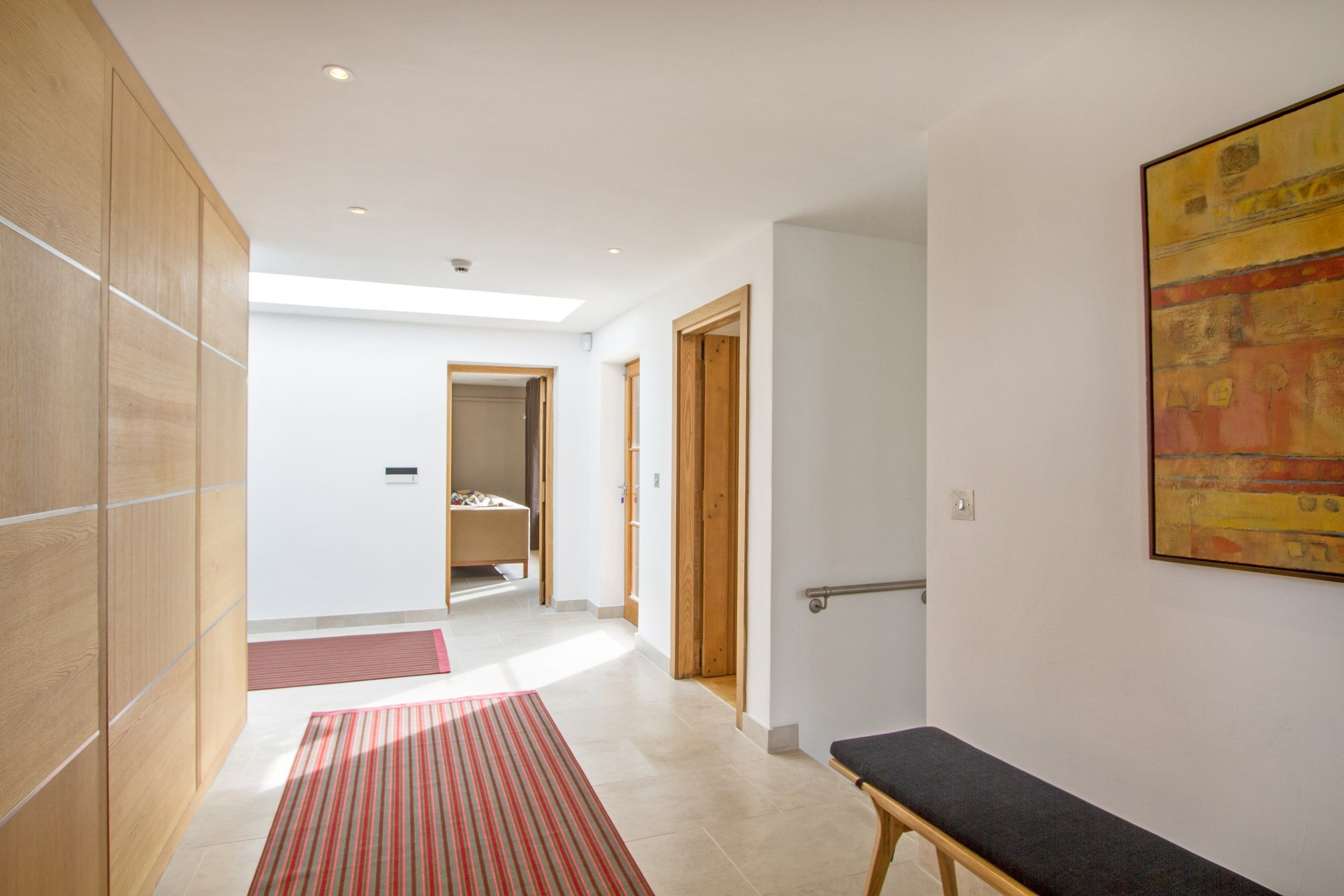 New hallway with pale stone floor and oak doors leading through the ground floor, listed country house, Chiddingfold.