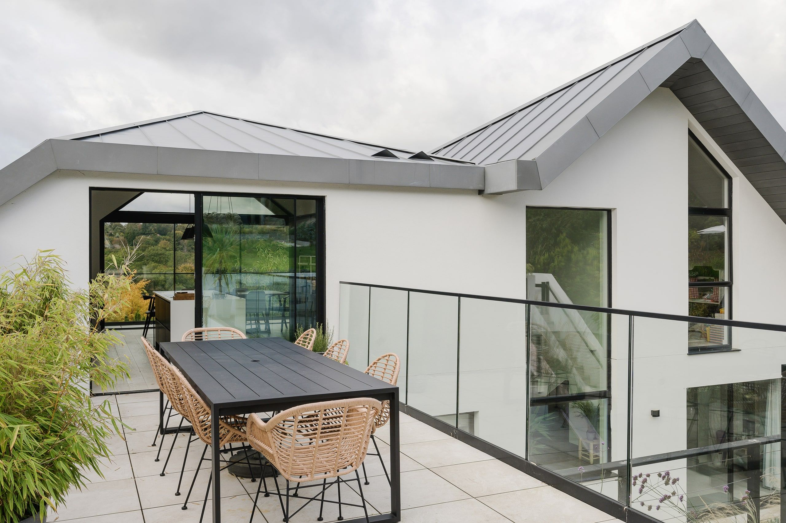 Roof terrace and dining table beneath the zinc scissor roof and glass balustrade, upside down house, Haslemere.