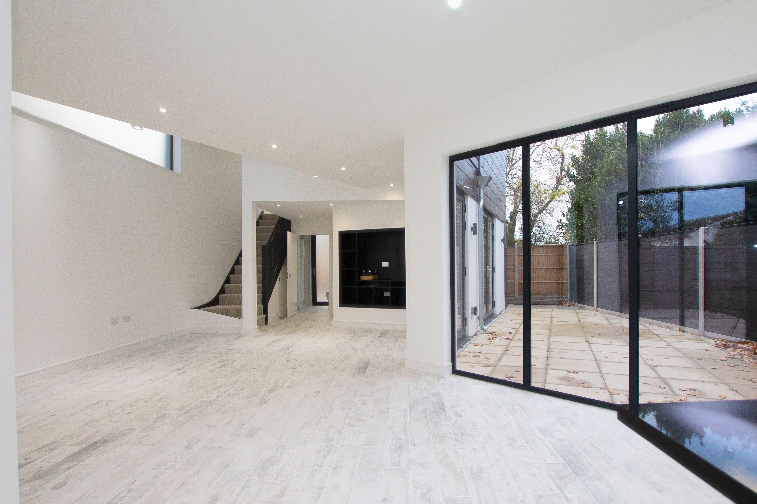Living space with full-height glazing to the terrace and the staircase beyond, new build retirement house, Fareham.