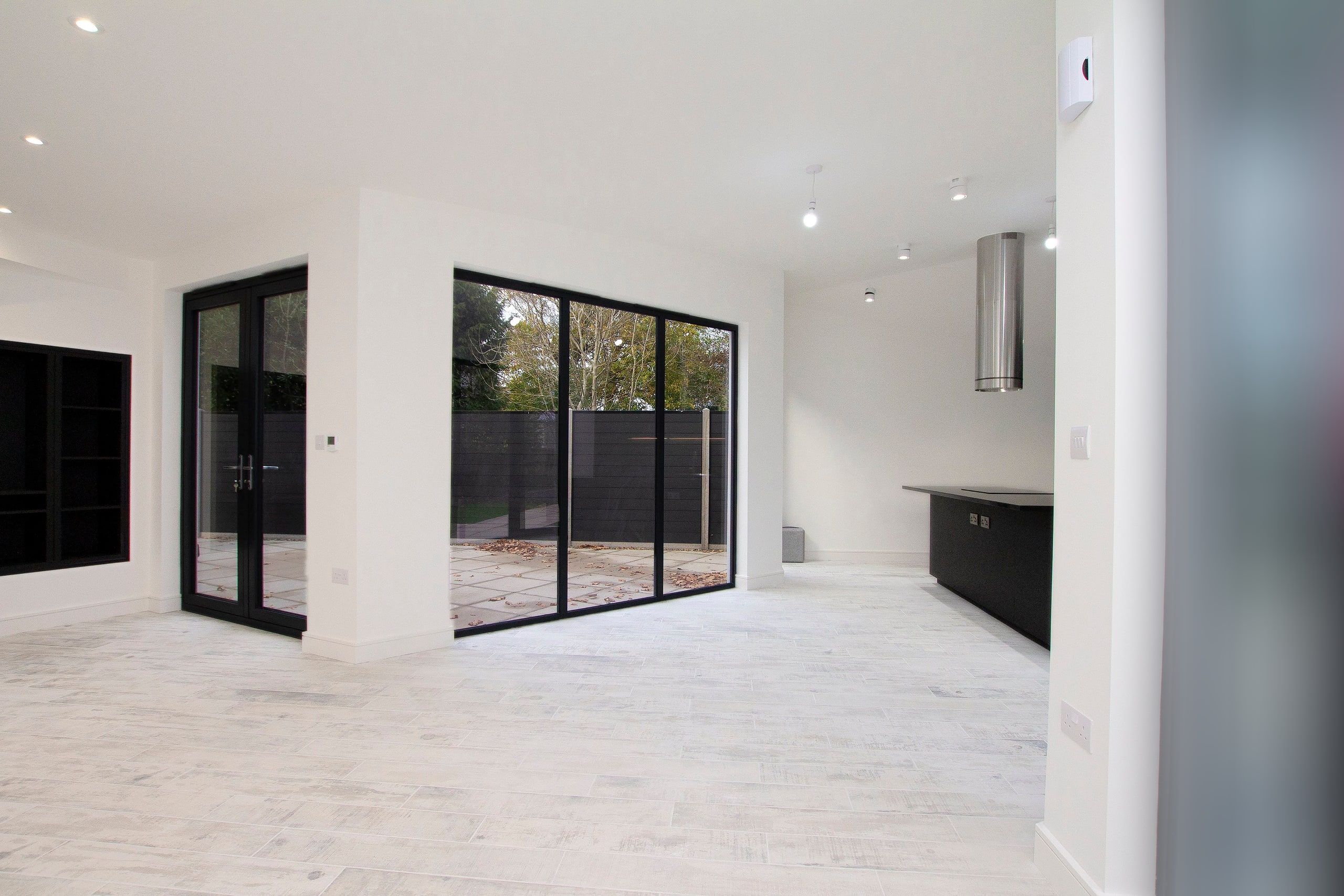 Glazed doors to the terrace with the kitchen beyond across the pale timber floor, new build retirement house, Fareham.