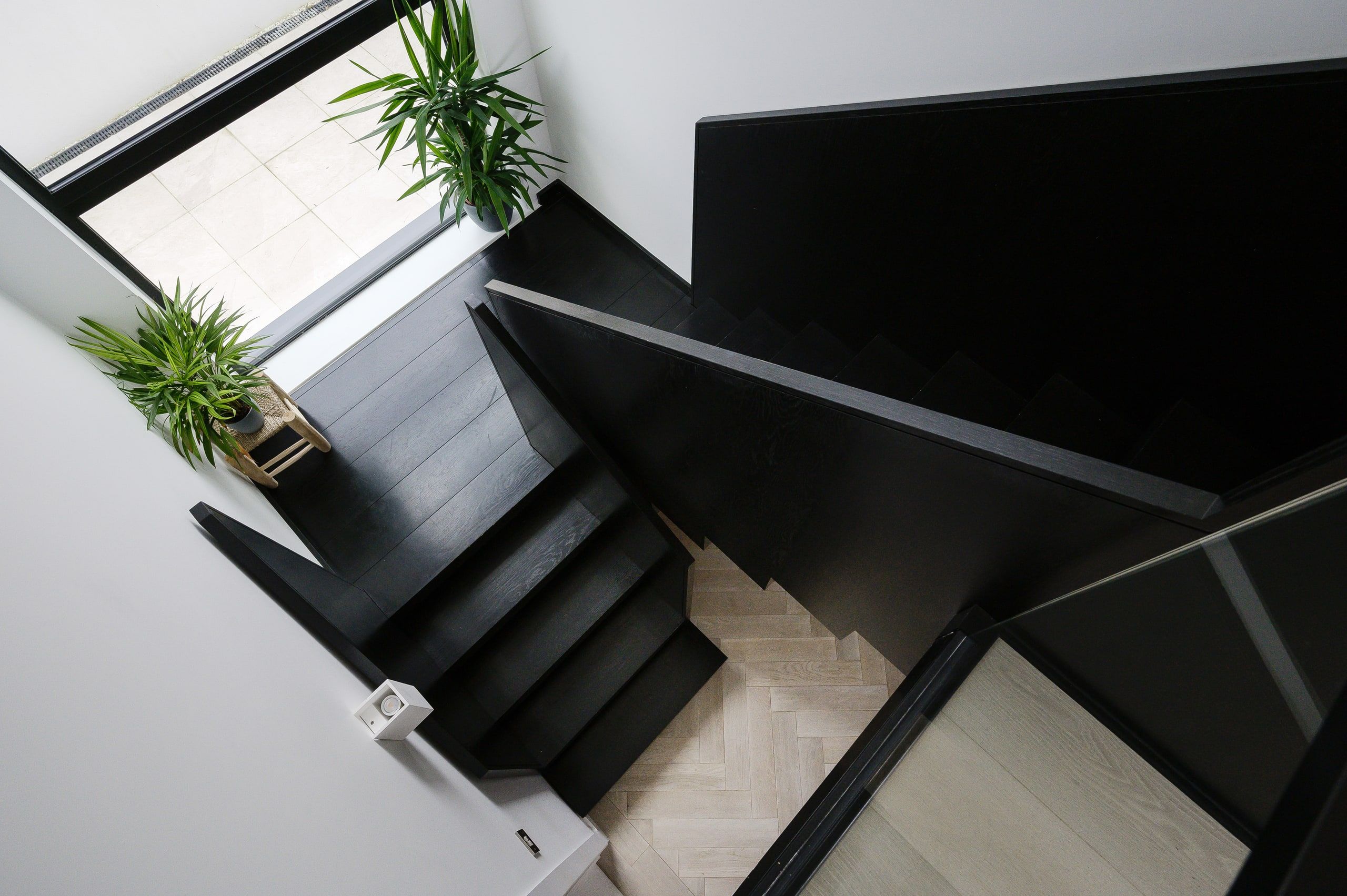 Looking down the black timber staircase to the herringbone floor below, upside down house, Haslemere.