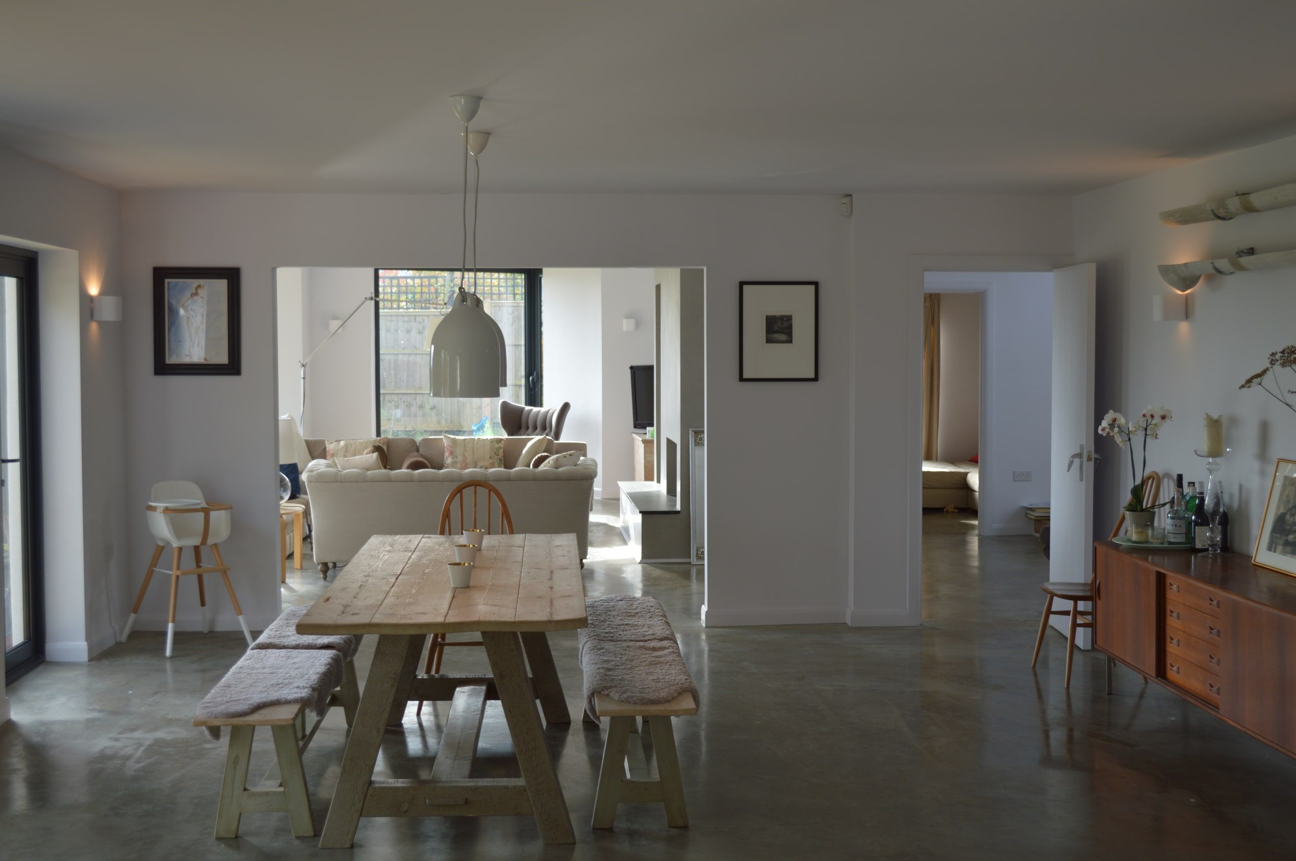 Dining table on the polished concrete floor with vistas through the open-plan ground floor, 1960s house, Lodsworth.