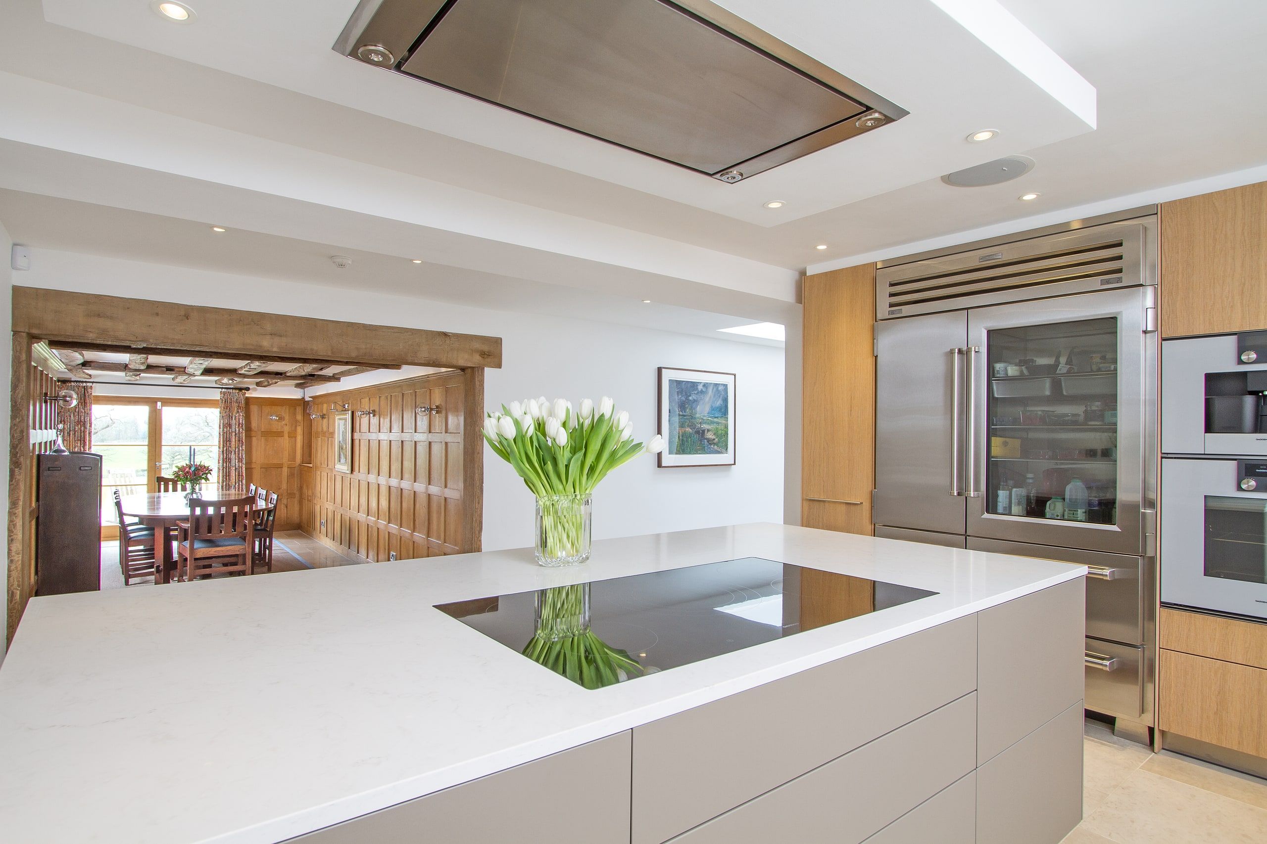Kitchen island with induction hob and flush ceiling extract, dining room beyond, listed country house, Chiddingfold.