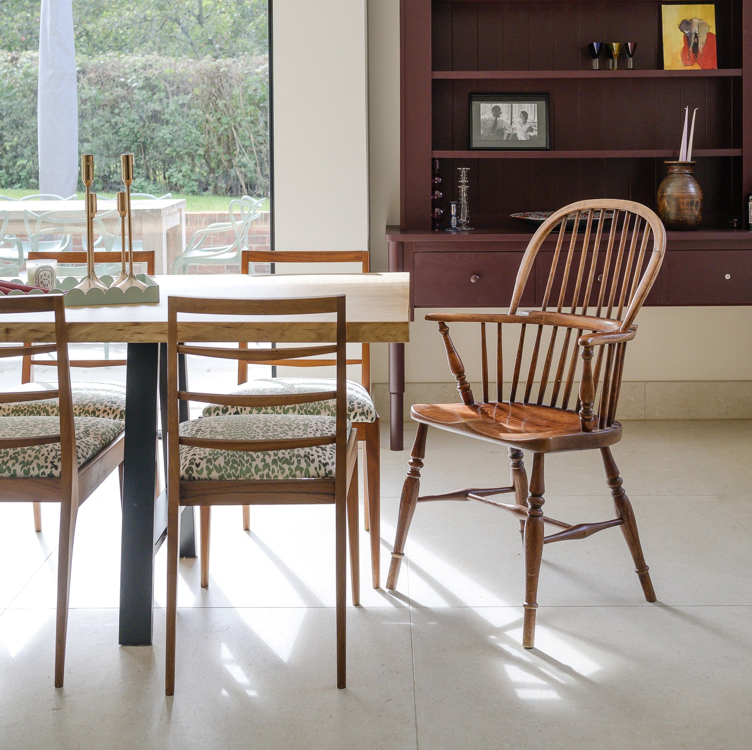A Windsor armchair and dining chairs beside the deep red built-in dresser, country house, Lodsworth.