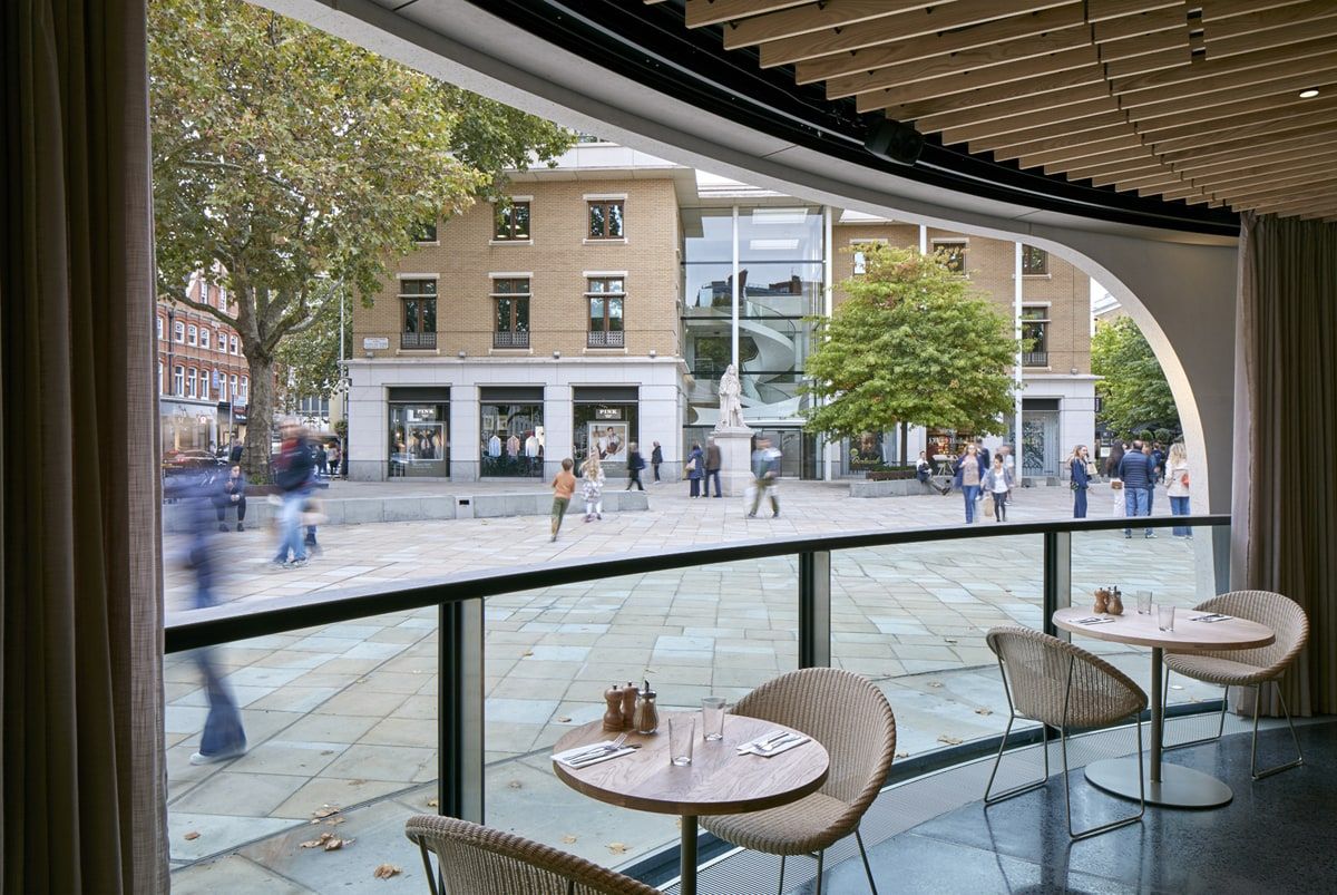 View along the inside of the curved glazing to the shopfronts opposite, restaurant pavilion, Duke of York Square, London.
