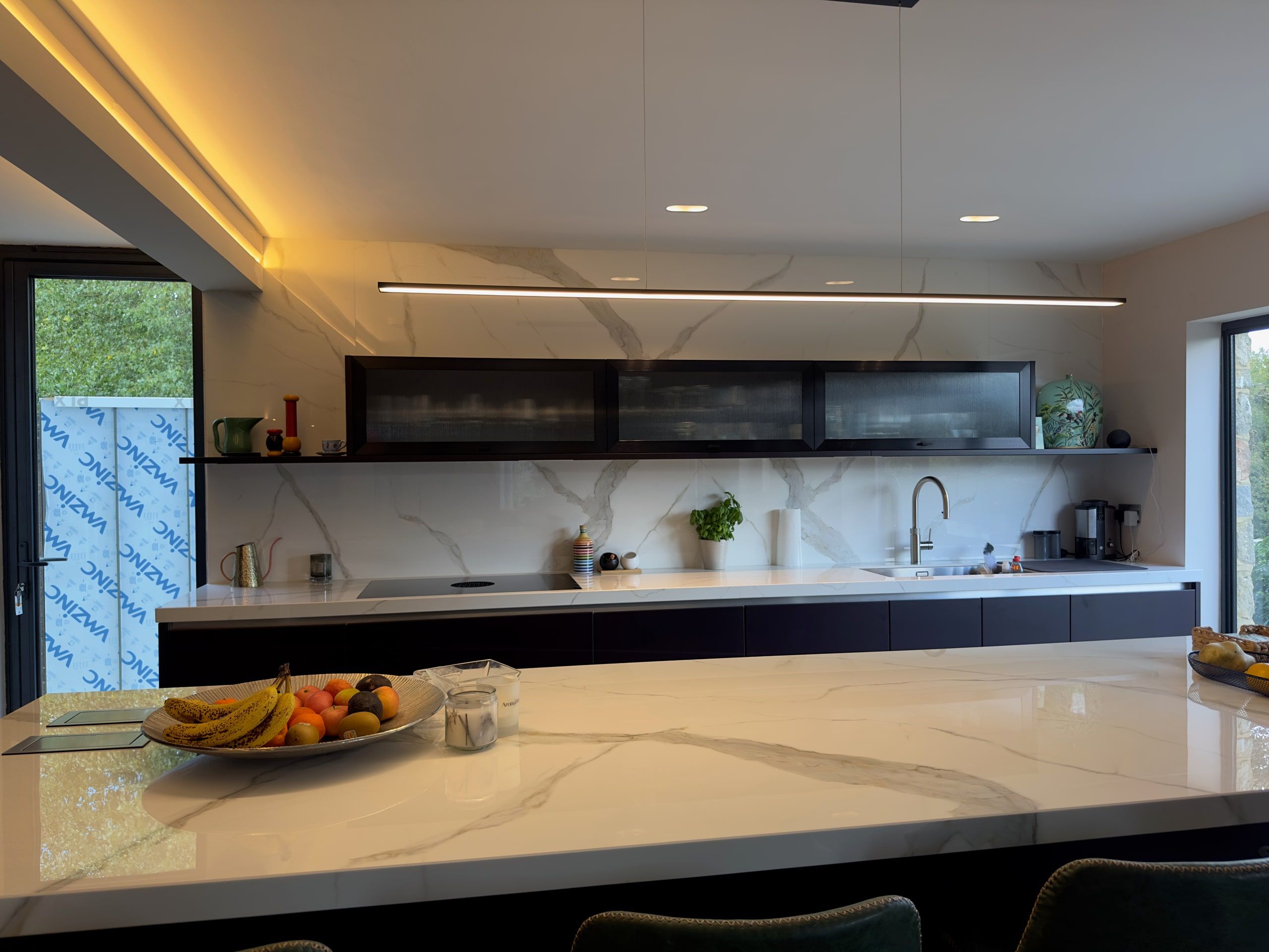 Marble worktop and glazed wall cabinets along the kitchen run, 1960s house, Lodsworth.