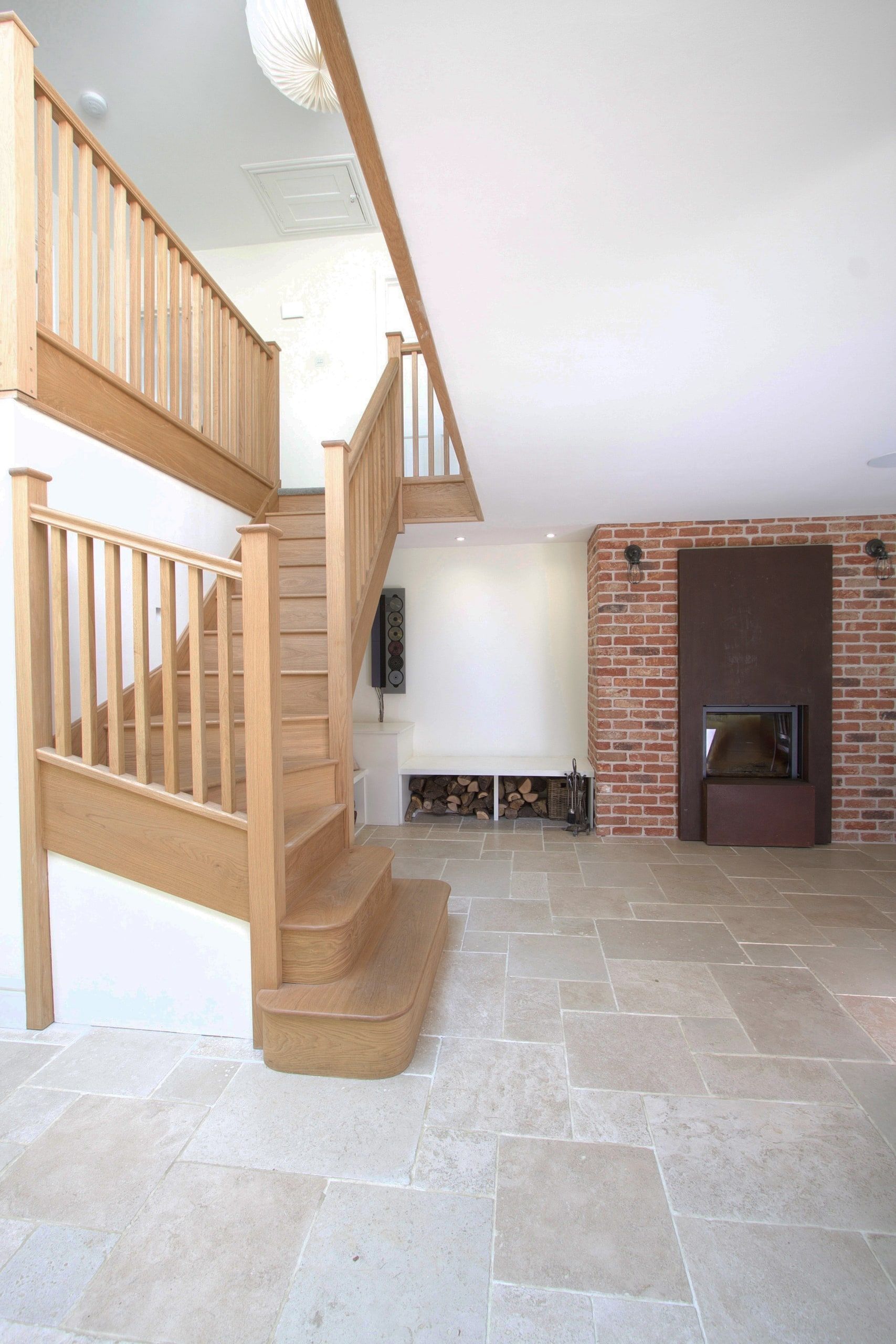 Oak staircase beside the brick chimney breast and wood-burning stove, 1930s country house, Mole Valley.