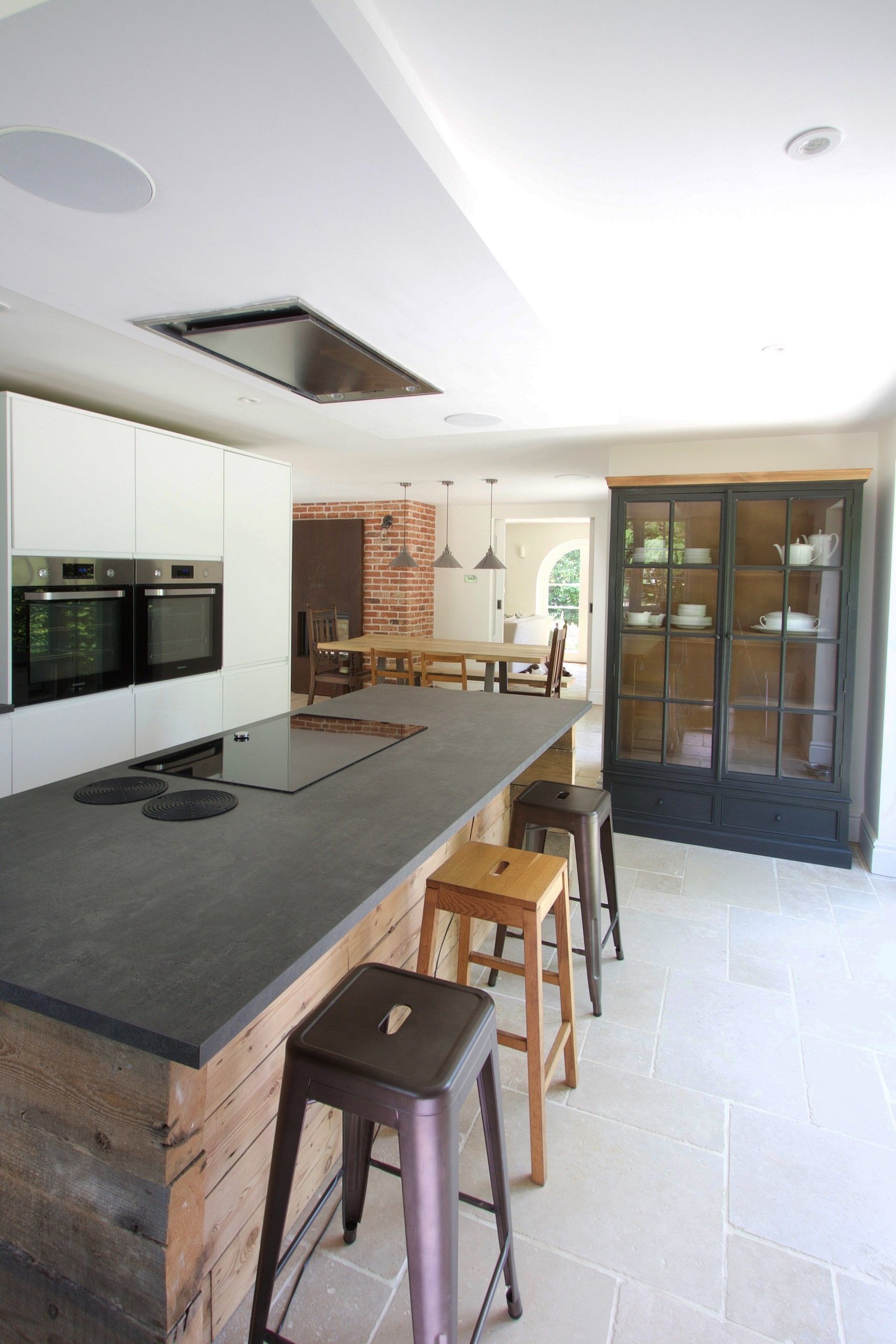 Kitchen island with induction hob, tall ovens and a glazed dresser, 1930s country house, Mole Valley.