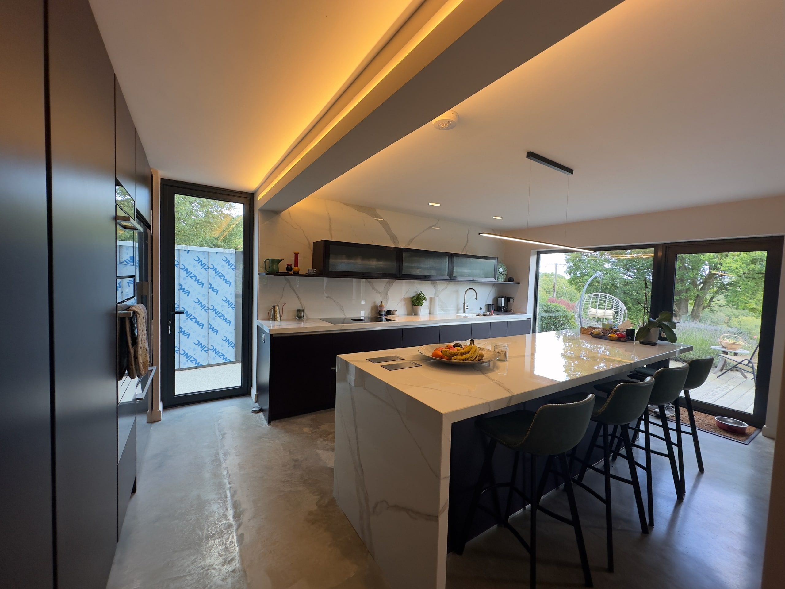 Kitchen island looking out to the garden through sliding glazed doors, 1960s house, Lodsworth.