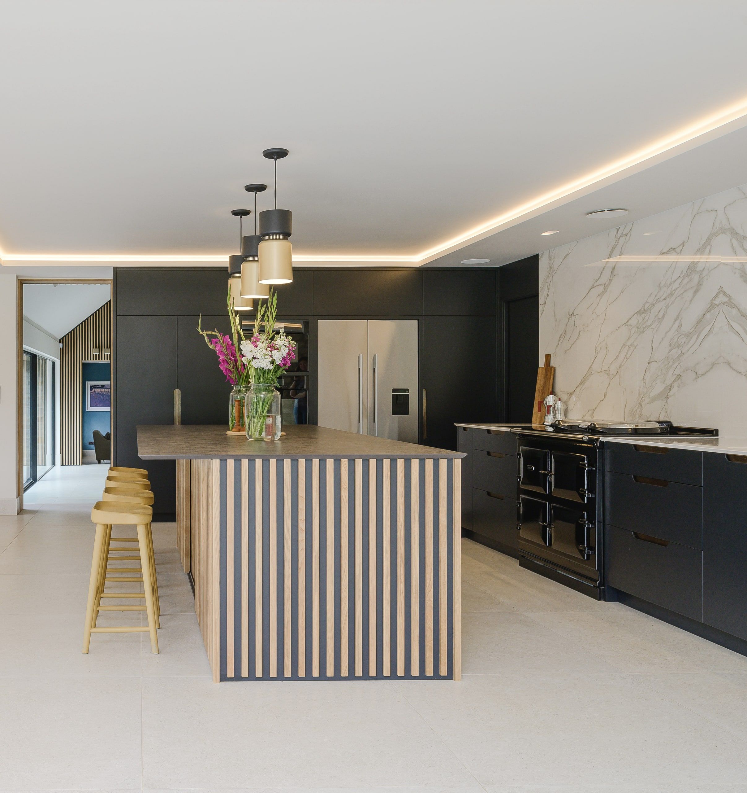 Kitchen island in oak battens with black cabinetry, marble splashback and range, country house, Lodsworth.