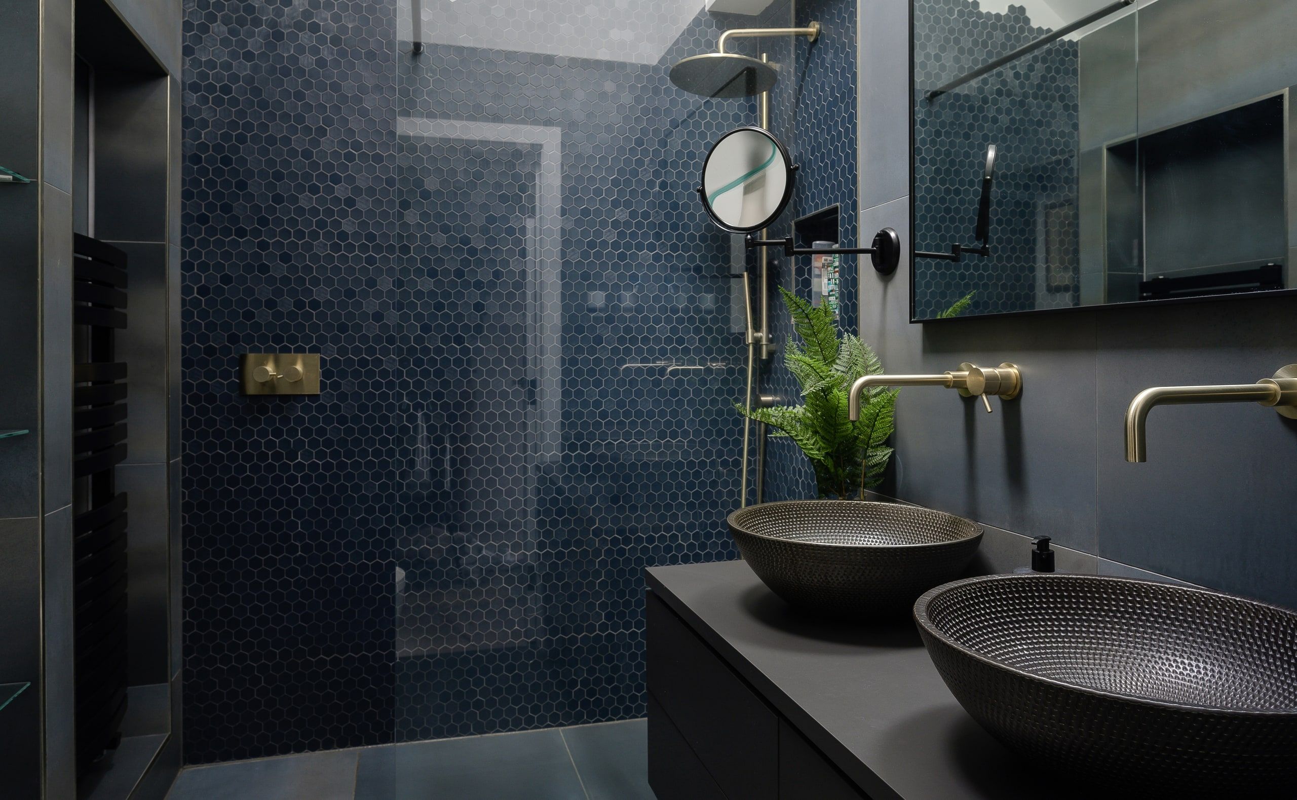 Shower room lined in dark blue hexagonal mosaic with brass taps and hammered metal basins, upside down house, Haslemere.