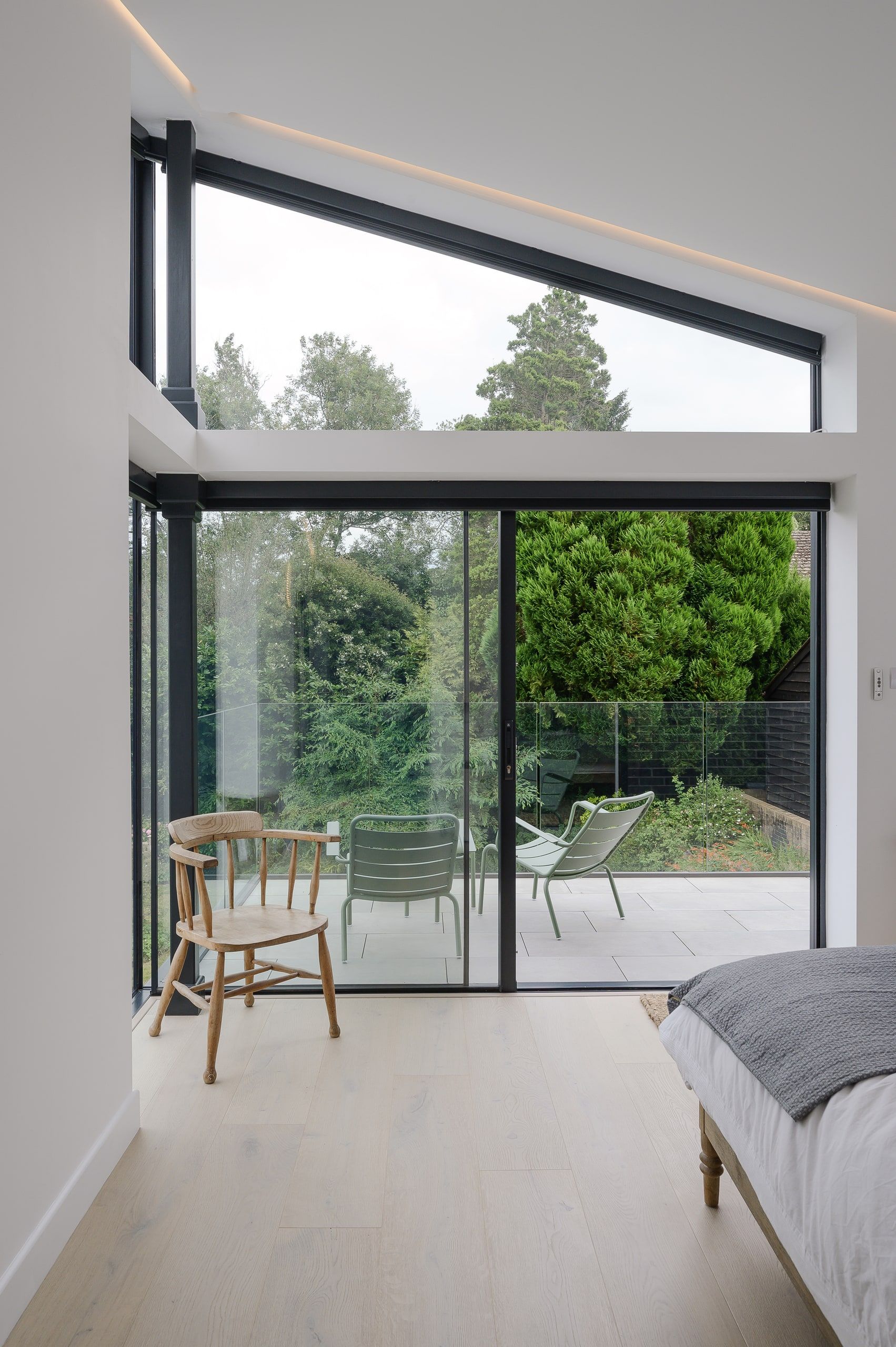 Bedroom corner with sliding doors and a triangular clerestory window over the terrace, 1960s house, Haslemere.