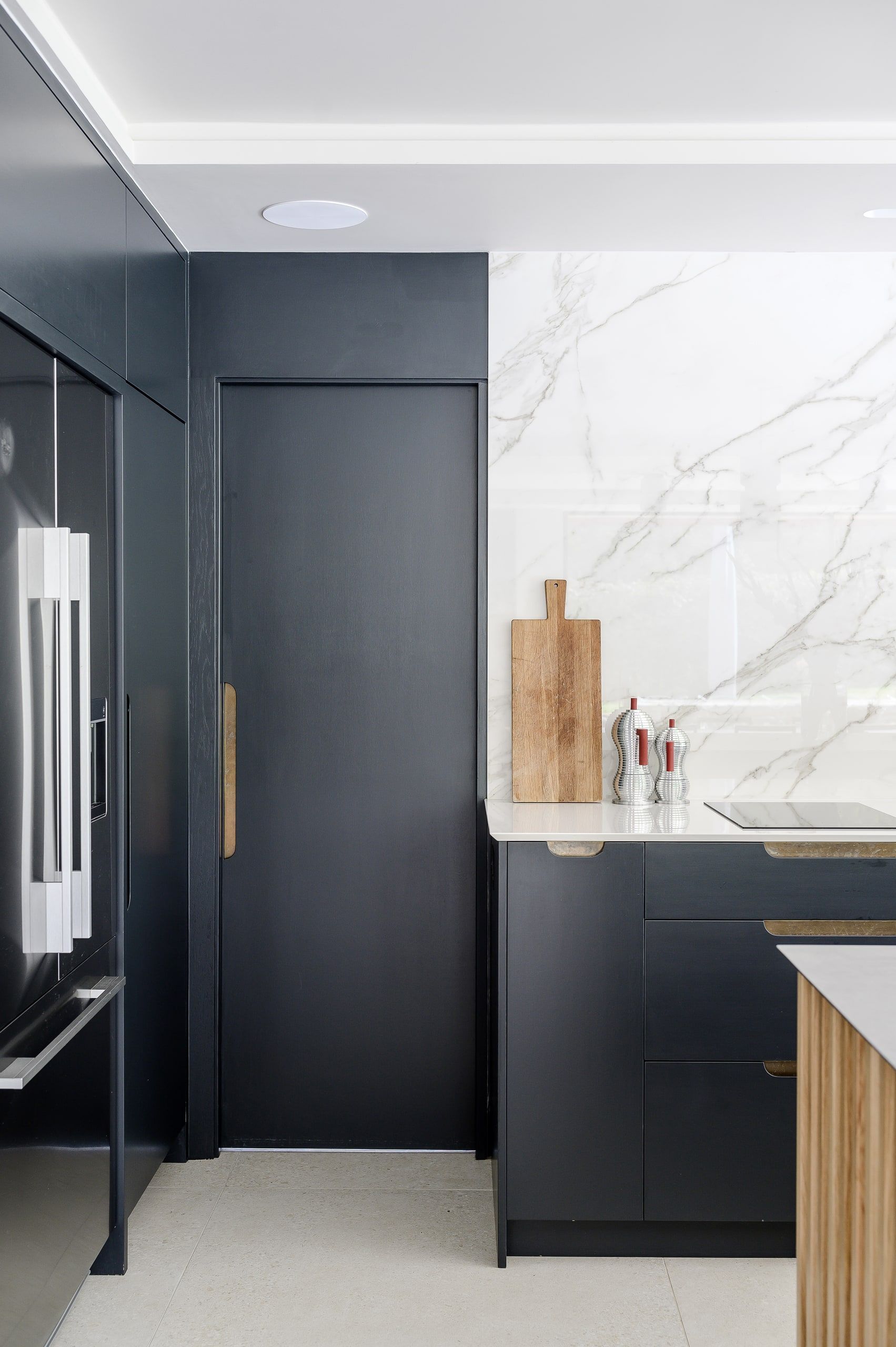 Concealed pantry door in dark blue joinery beside the marble splashback, country house, Lodsworth.