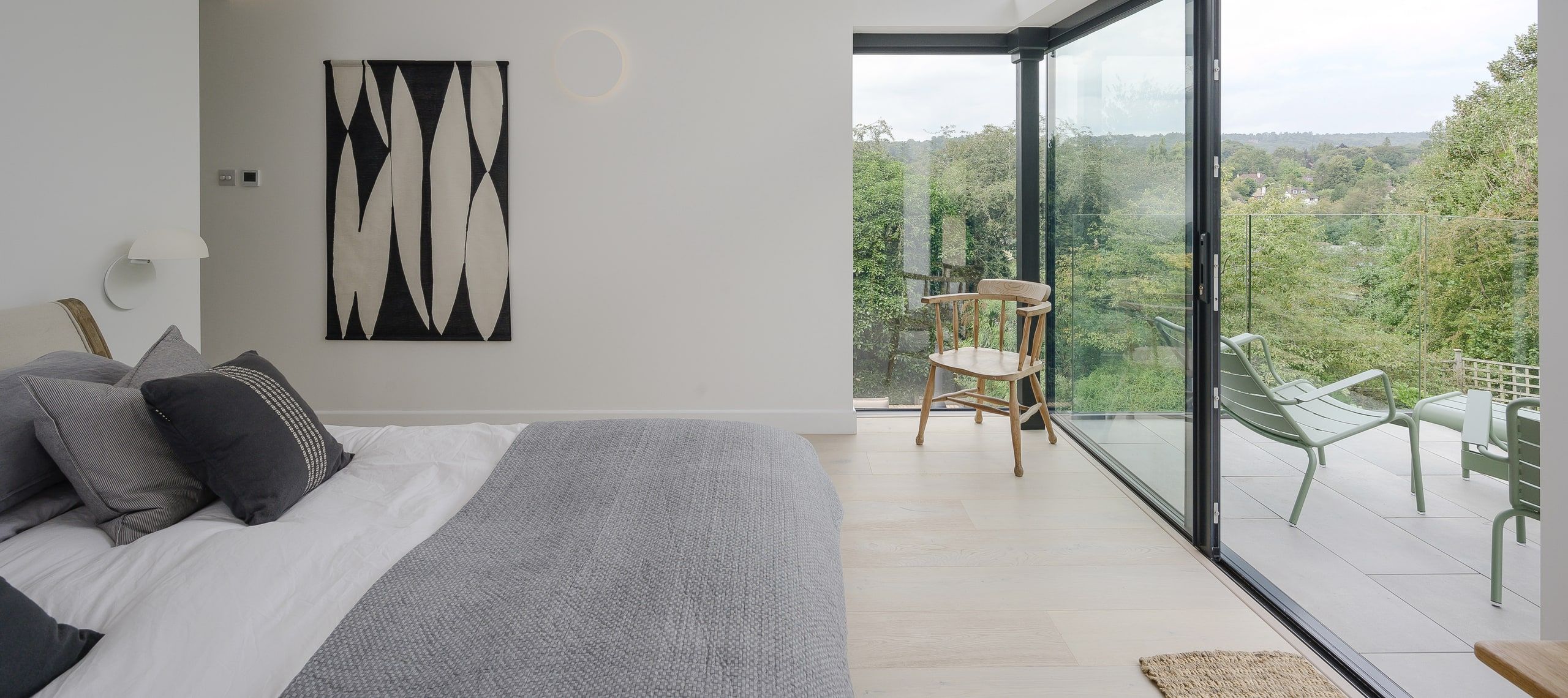 Main bedroom opening through sliding glass onto the roof terrace and treetop view, 1960s house, Haslemere.