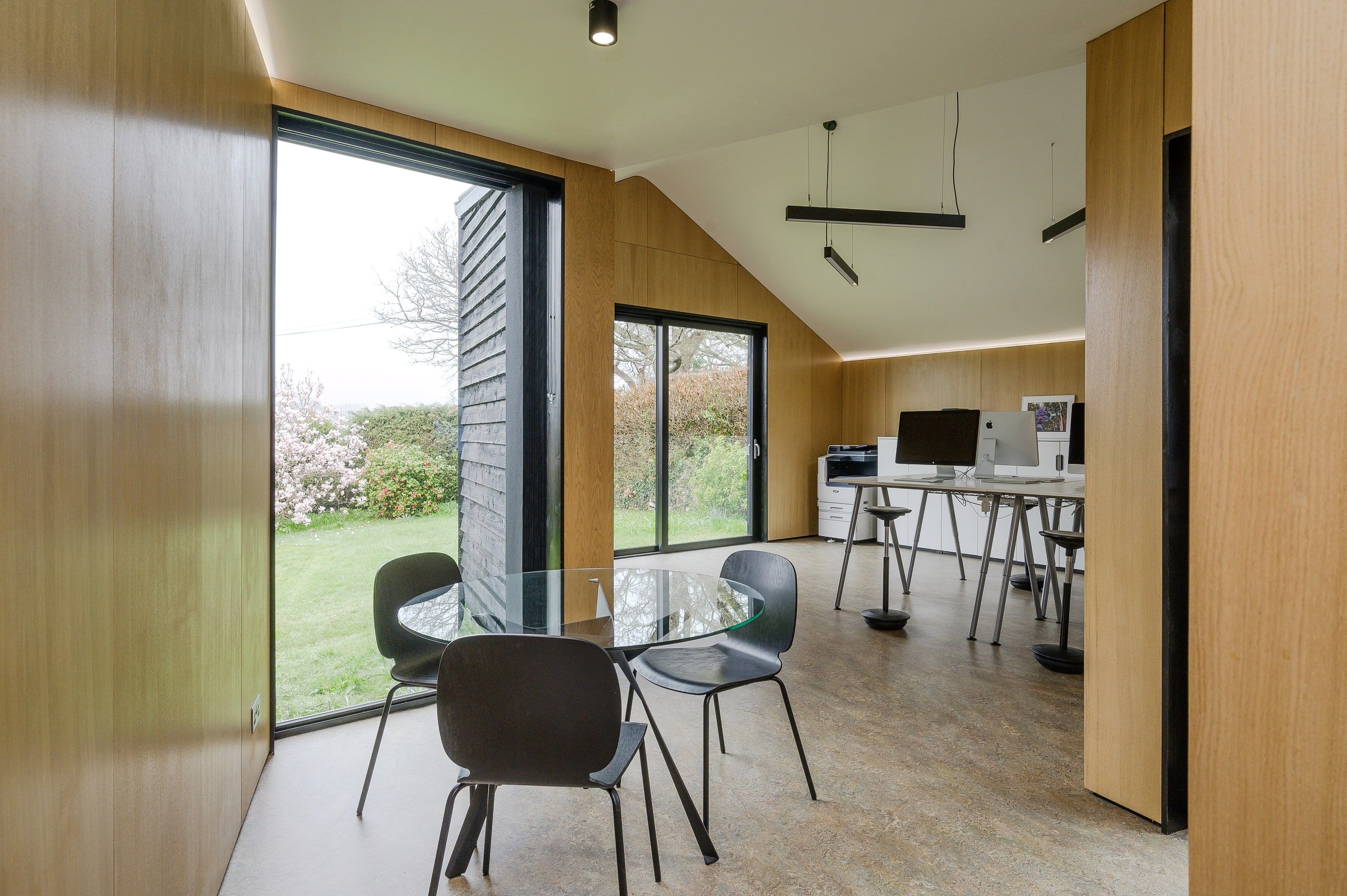 Oak-lined studio with a meeting table and a glazed door to the garden, 1960s house, Fernhurst.