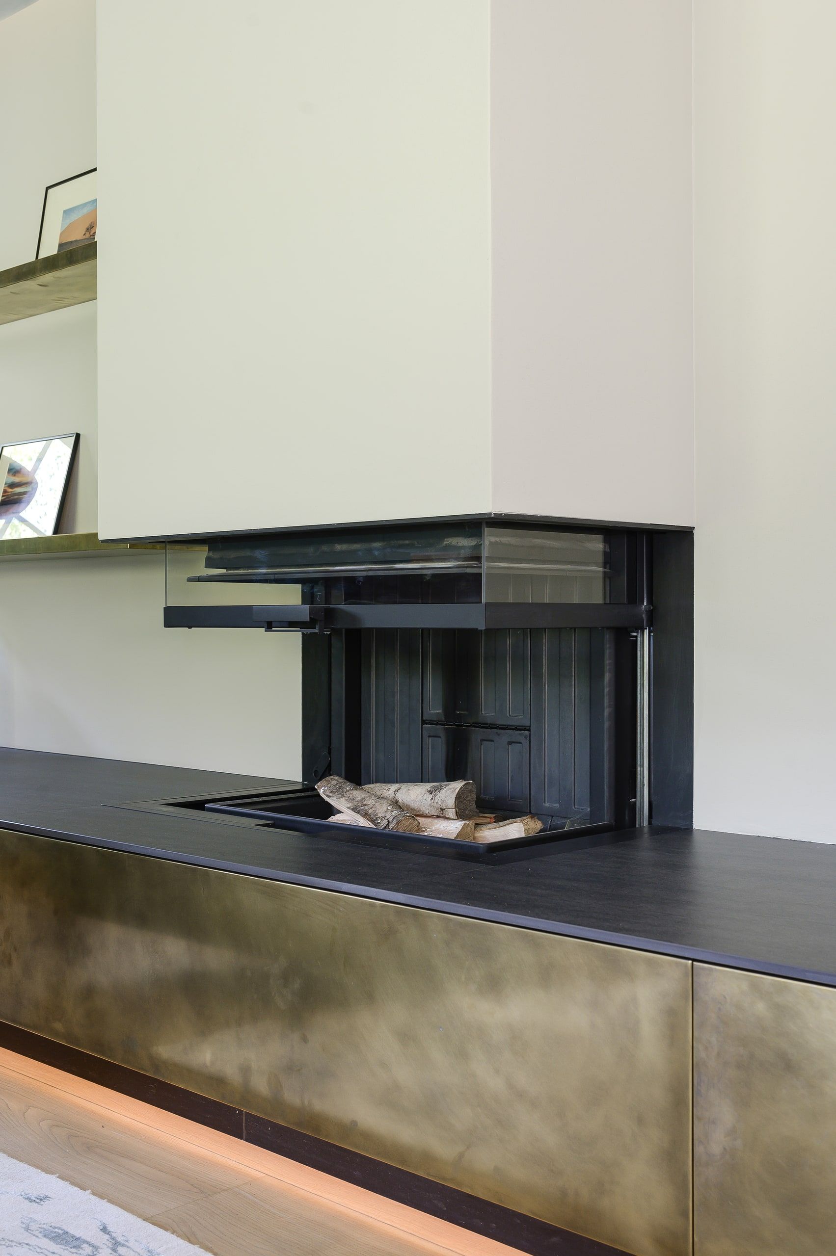 Inset log fire above a brass-fronted media unit with concealed lighting, country house, Lodsworth.
