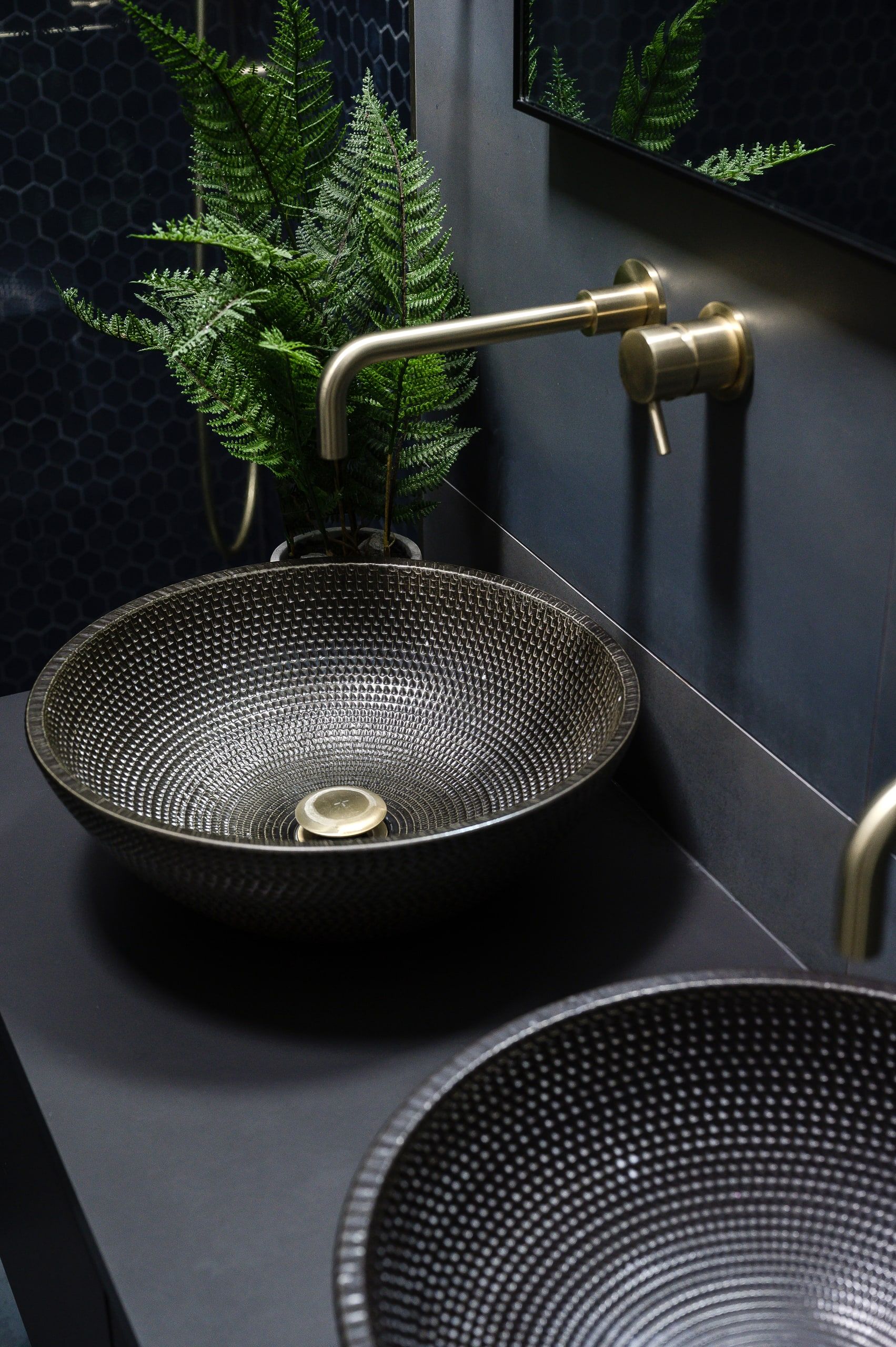 Hammered metal basins and brass wall tap against dark blue mosaic tiling, upside down house, Haslemere.