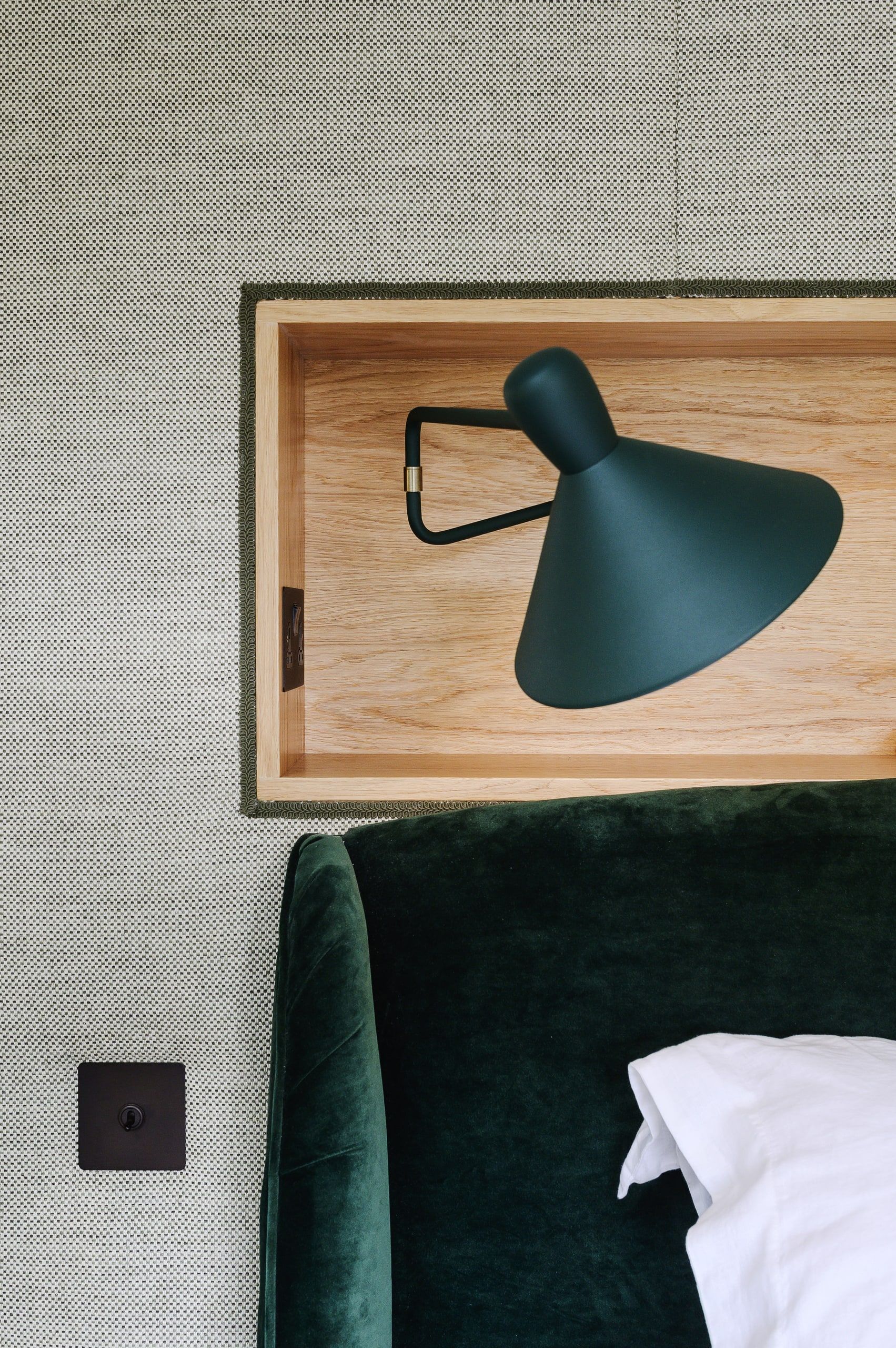 Close view of a dark green wall light in the oak headboard recess above the bed, country house, Lodsworth.