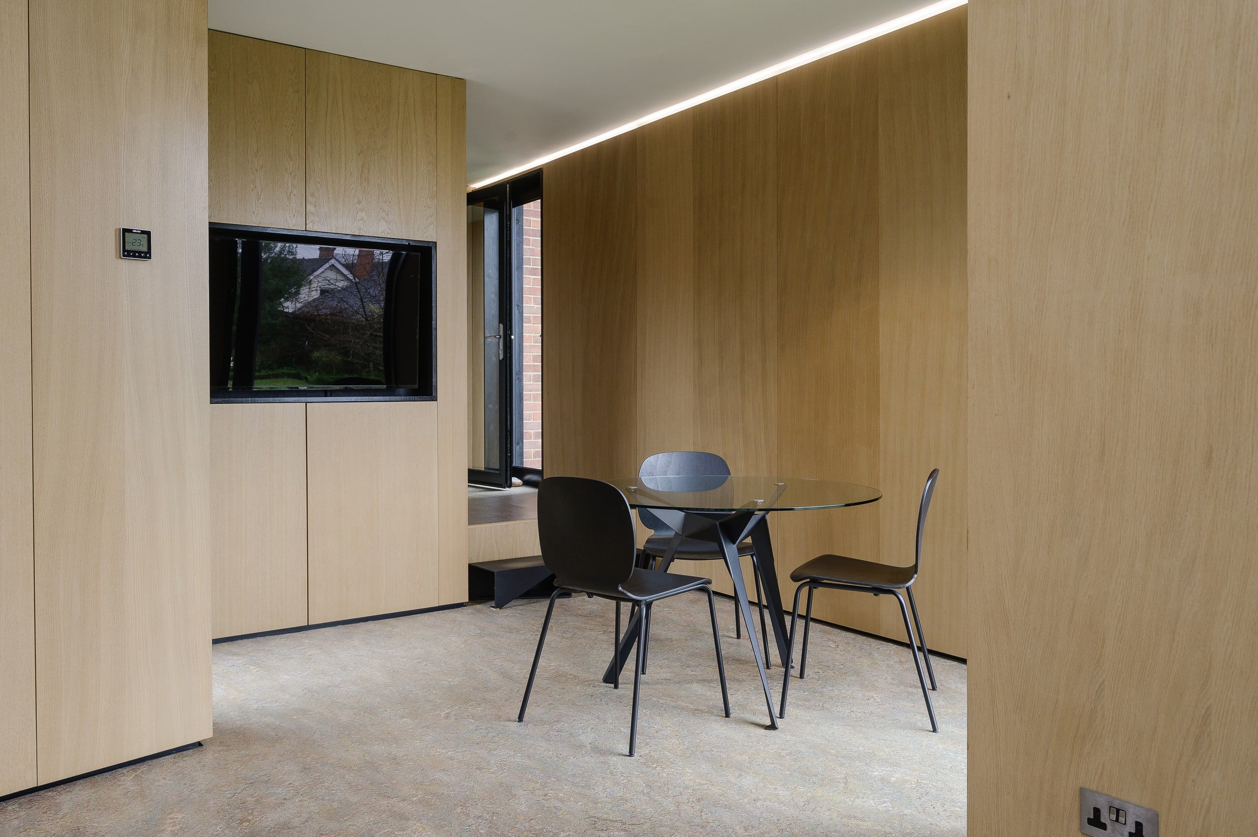 Oak joinery wall and framed window beside the studio meeting table, 1960s house, Fernhurst.