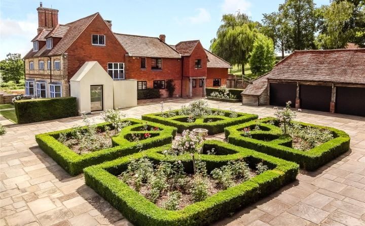 Clipped box parterre in front of the restored facades and chimney, Grade II listed country house, Chiddingfold.