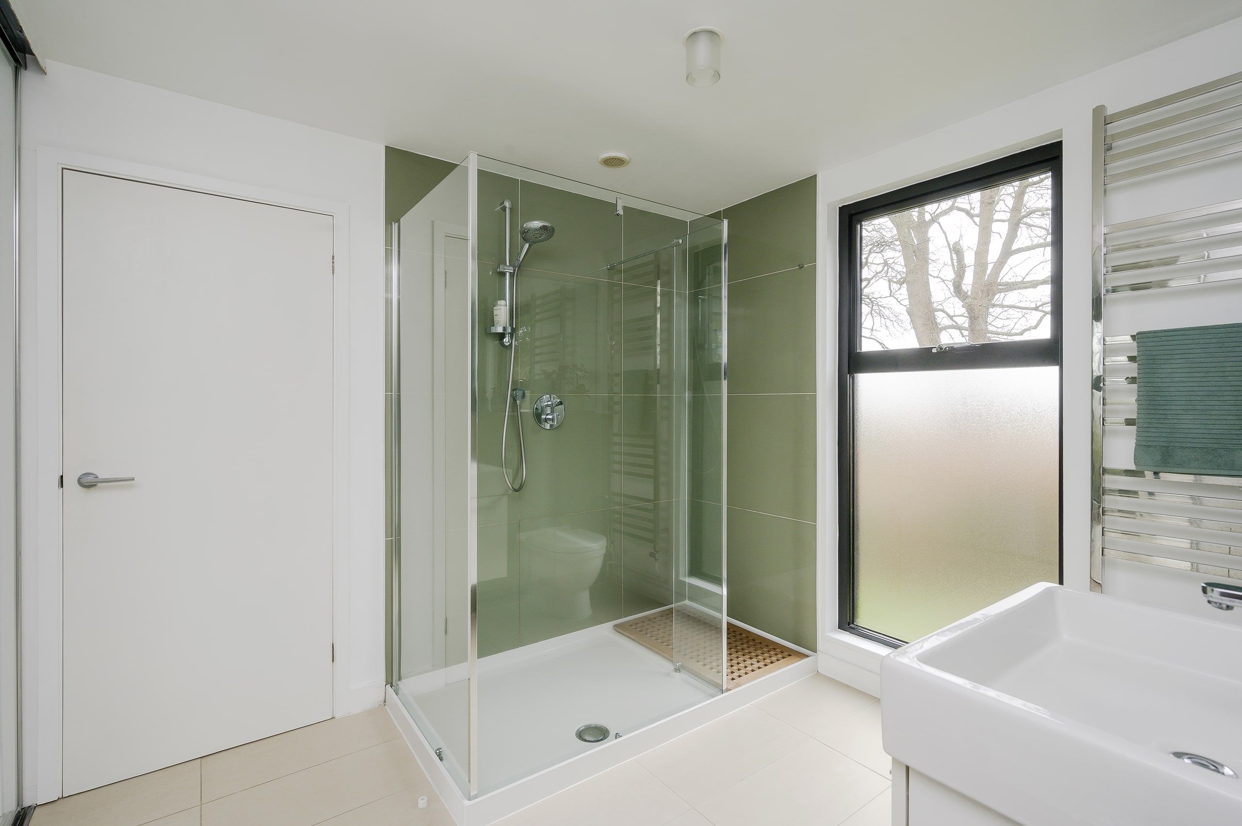 Glazed walk-in shower enclosure in the white-tiled shower room, 1960s house, Fernhurst.
