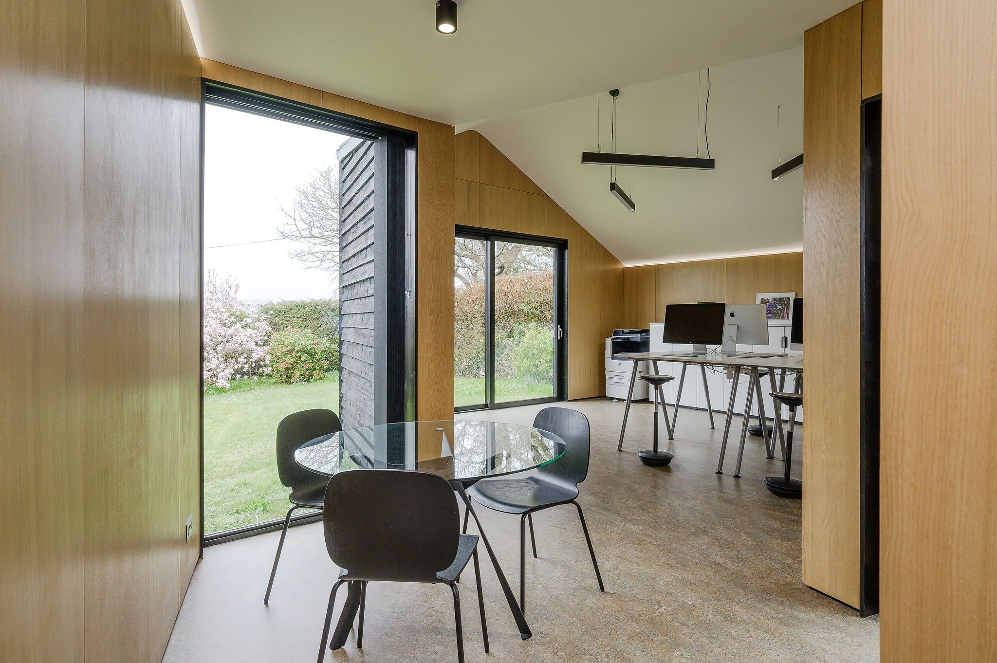 View past the meeting table to the desks, blossom in the garden beyond, ArchitectureLIVE studio, Fernhurst